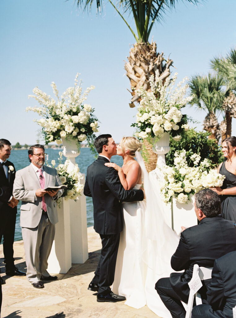 First kiss under the floral arch with lake view in background